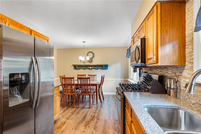 2400 James St, Hopewell Twp Bea, PA 15001 - kitchen featuring appliances with stainless steel finishes, a sink, brown cabinets, light wood finished floors, and a chandelier