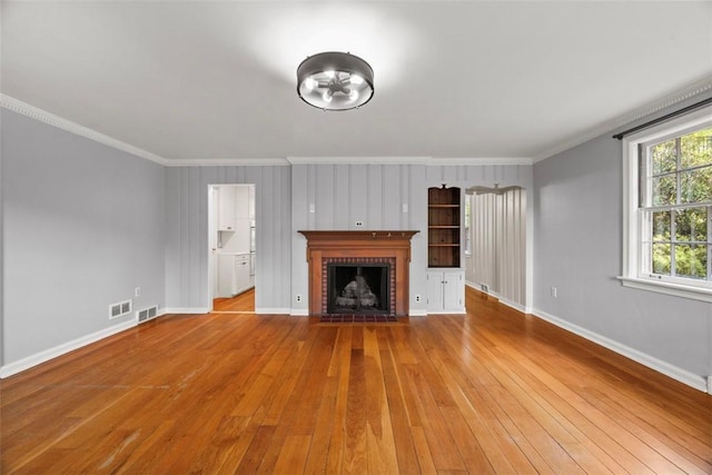 1509 Walnut St, Edgewood, PA 15218 - unfurnished living room featuring crown molding, baseboards, wood-type flooring, and a brick fireplace