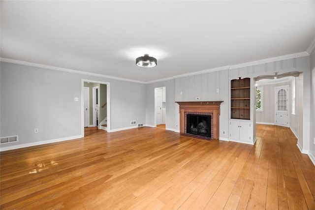 1509 Walnut St, Edgewood, PA 15218 - unfurnished living room featuring crown molding, light wood-type flooring, baseboards, a brick fireplace, and stairs