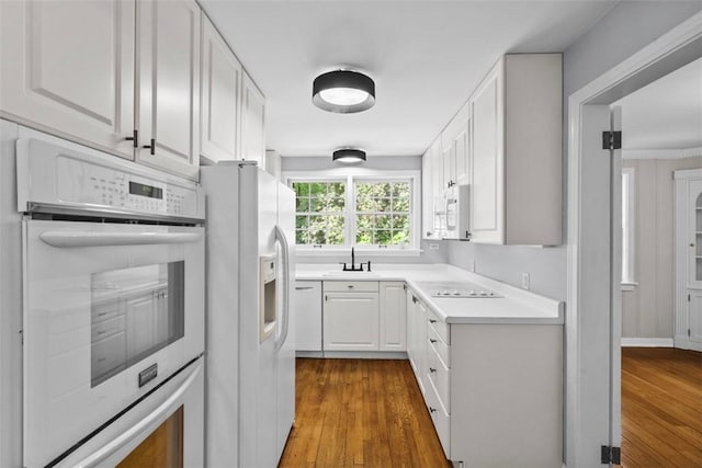 1509 Walnut St, Edgewood, PA 15218 - kitchen with white appliances, dark wood-type flooring, white cabinets, light countertops, and a sink