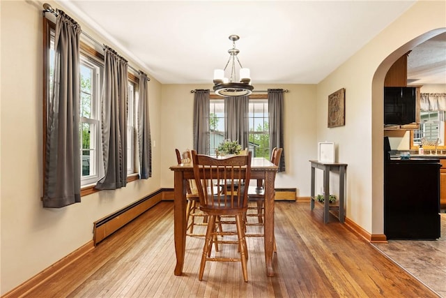 4624 Clear Shade Dr, Windber, PA 15963 - dining area featuring a baseboard heating unit, a chandelier, arched walkways, light wood-style floors, and healthy amount of natural light