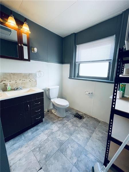 471 Lincoln Ave, Bellevue, PA 15202 - bathroom featuring toilet, vanity, and decorative backsplash