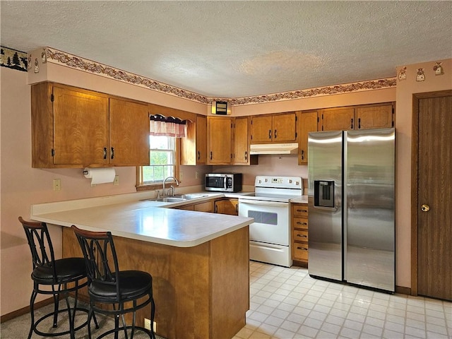 495 Glendale Rd, North Sewickley Twp, PA 15010 - kitchen with appliances with stainless steel finishes, a sink, brown cabinets, under cabinet range hood, and a peninsula