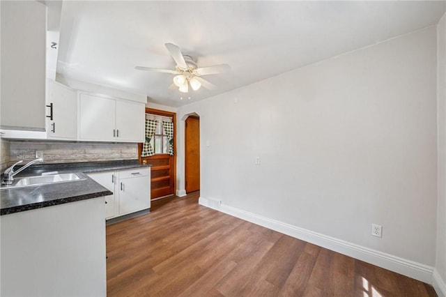 134 Hamilton Dr, Penn Hills, PA 15235 - kitchen with a sink, dark countertops, arched walkways, white cabinets, and backsplash