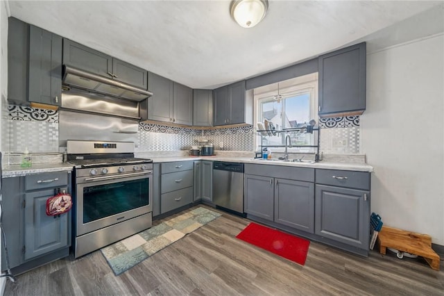 3003 Jersey St, Mckeesport, PA 15132 - kitchen featuring stainless steel appliances, a sink, under cabinet range hood, gray cabinetry, and dark wood finished floors
