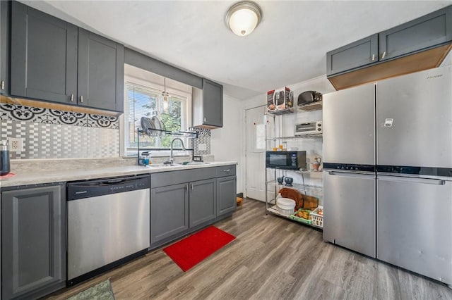 3003 Jersey St, Mckeesport, PA 15132 - kitchen featuring appliances with stainless steel finishes, a sink, wood finished floors, light countertops, and backsplash