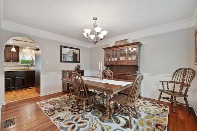 205 Emily Dr, Cranberry Twp, PA 16066 - dining room with arched walkways, a chandelier, wood finished floors, and crown molding