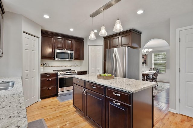 205 Emily Dr, Cranberry Twp, PA 16066 - kitchen featuring appliances with stainless steel finishes, arched walkways, light wood finished floors, dark brown cabinetry, and a kitchen island