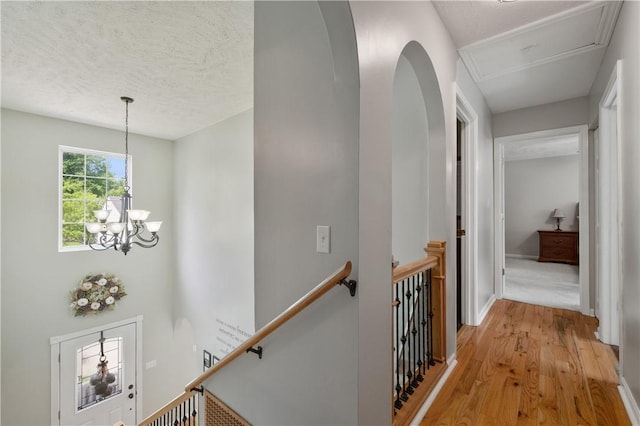 205 Emily Dr, Cranberry Twp, PA 16066 - hall featuring an upstairs landing, light wood-style flooring, a chandelier, a textured ceiling, and attic access