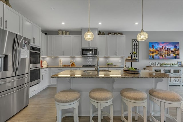 2054 Cade Dr, Potter Twp, PA 15061 - kitchen with appliances with stainless steel finishes, a sink, tasteful backsplash, a breakfast bar area, and dark stone counters