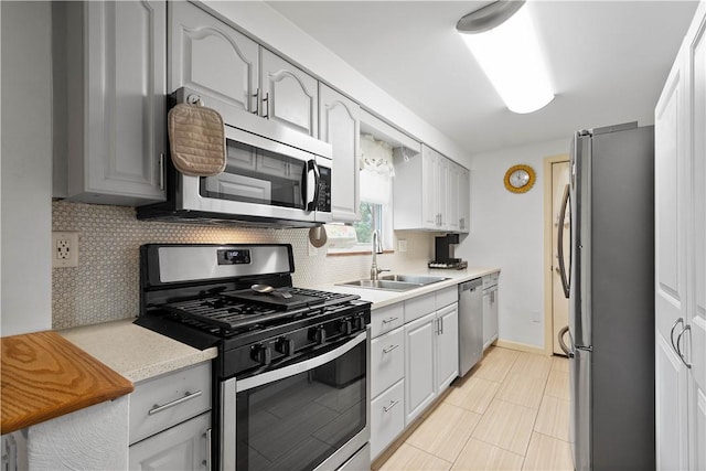 260 Bluemont Dr, West Mifflin, PA 15122 - kitchen featuring stainless steel appliances, a sink, light countertops, tasteful backsplash, and baseboards