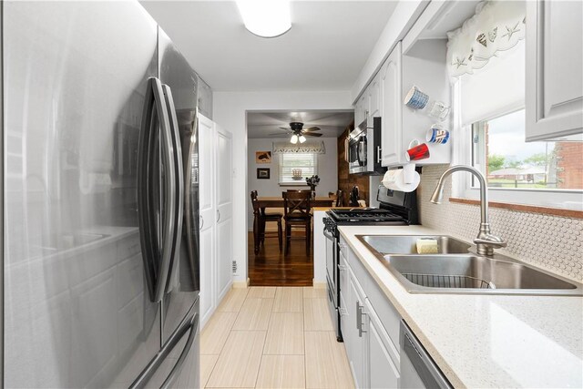 260 Bluemont Dr, West Mifflin, PA 15122 - kitchen featuring appliances with stainless steel finishes, a sink, ceiling fan, tasteful backsplash, and white cabinets