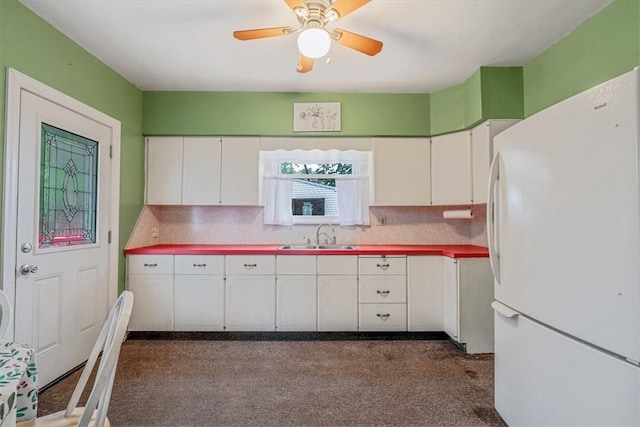 1675 Clairton Rd, West Mifflin, PA 15122 - kitchen featuring freestanding refrigerator, a sink, white cabinetry, dark colored carpet, and tasteful backsplash