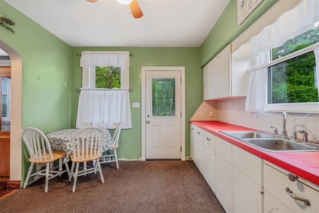 1675 Clairton Rd, West Mifflin, PA 15122 - kitchen with arched walkways, a sink, white cabinets, a ceiling fan, and carpet floors