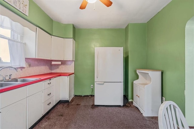 1675 Clairton Rd, West Mifflin, PA 15122 - kitchen with freestanding refrigerator, a sink, dark carpet, white cabinetry, and ceiling fan