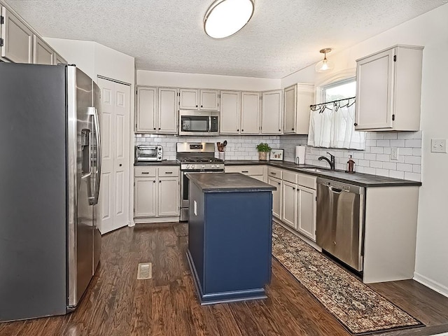 104 Rylie Dr, Jackson Twp But, PA 16037 - kitchen featuring appliances with stainless steel finishes, dark countertops, dark wood-style flooring, a kitchen island, and a textured ceiling