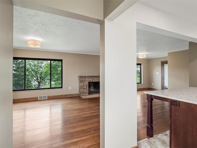 330 Center Grange Rd, Center Twp Bea, PA 15061 - unfurnished living room with a textured ceiling, wood finished floors, crown molding, baseboards, and a stone fireplace