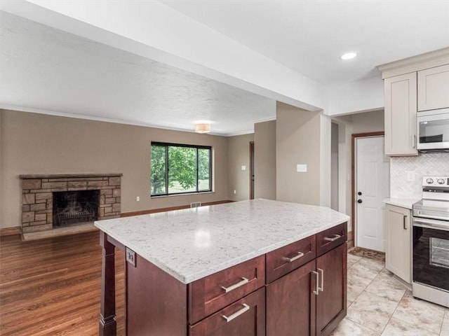 330 Center Grange Rd, Center Twp Bea, PA 15061 - kitchen featuring stainless steel electric range oven, white microwave, a fireplace, tasteful backsplash, and a center island