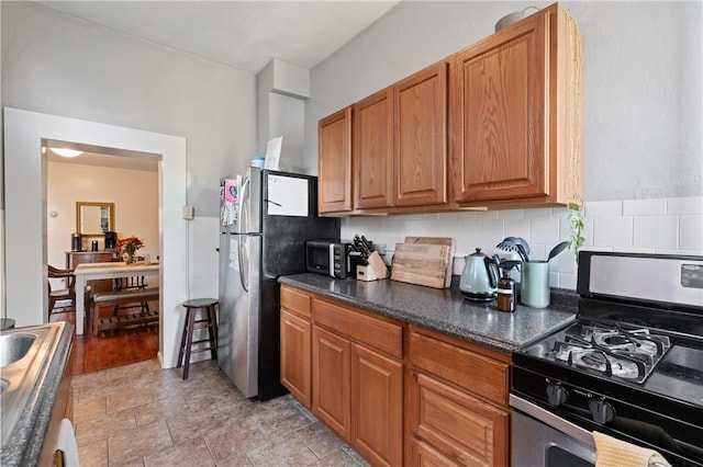 4123 Foster St, Lawrenceville, PA 15201 - kitchen featuring stainless steel appliances, dark countertops, brown cabinets, and decorative backsplash