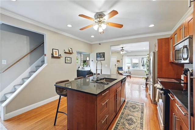 2511 Mission St, South Side, PA 15203 - kitchen featuring appliances with stainless steel finishes, a sink, a breakfast bar area, ceiling fan, and an island with sink