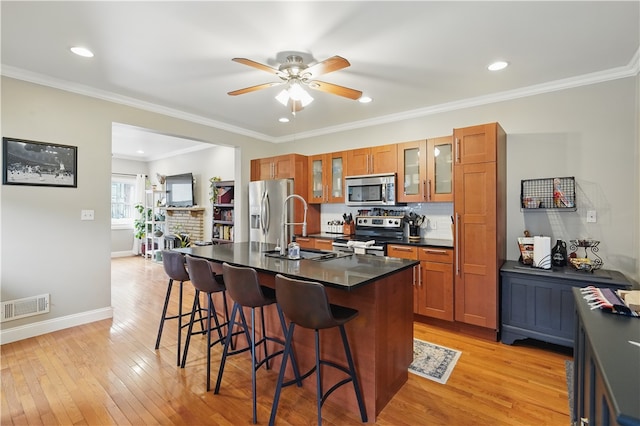 2511 Mission St, South Side, PA 15203 - kitchen with appliances with stainless steel finishes, brown cabinetry, a kitchen breakfast bar, dark countertops, and light wood-type flooring