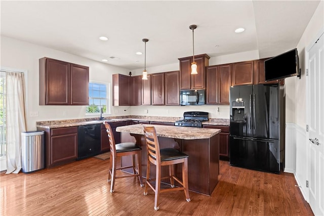 302 Pointe View Dr, Adams Twp, PA 16046 - kitchen with black appliances, a kitchen island, wood finished floors, a breakfast bar area, and hanging light fixtures