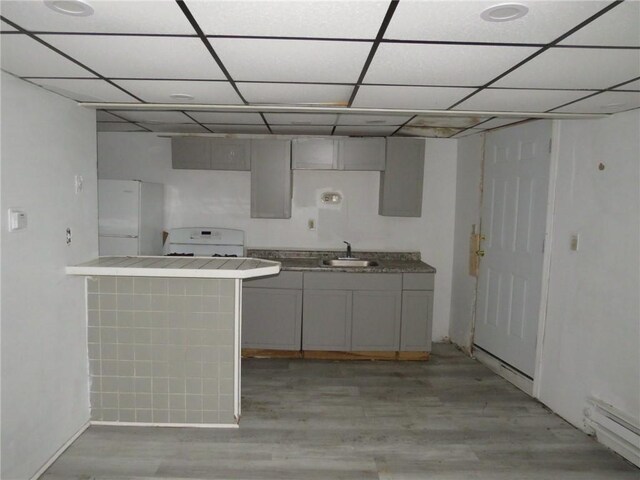 109 Parkfield St, Carrick, PA 15210 - kitchen with freestanding refrigerator, a sink, a baseboard radiator, light wood-type flooring, and a paneled ceiling