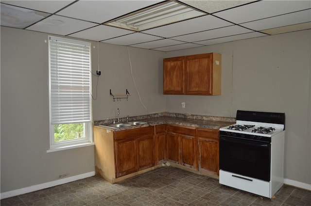 221 Friendship St, New Castle/5Th, PA 16101 - kitchen featuring white range with gas cooktop, a sink, a drop ceiling, brown cabinets, and baseboards