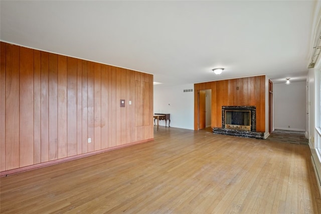 658 Bower Hill Rd, Peters Twp, PA 15367 - unfurnished living room featuring light wood-type flooring, wooden walls, and a fireplace with raised hearth