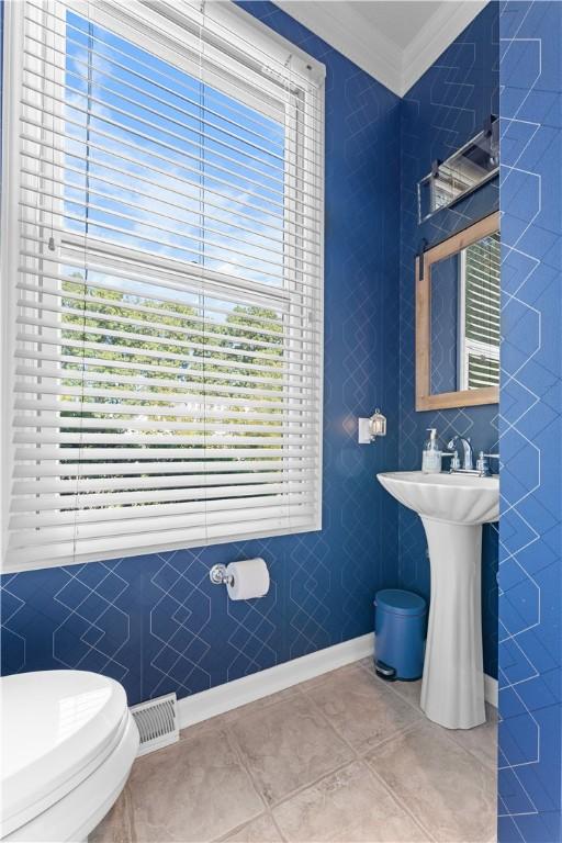122 Hunter Dr, Cranberry Twp, PA 16066 - half bathroom featuring crown molding, toilet, healthy amount of natural light, tile patterned flooring, and tile walls