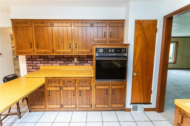 240 Connellsville St, Dunbar, PA 15431 - kitchen featuring black oven, light carpet, brown cabinets, light countertops, and light tile patterned floors