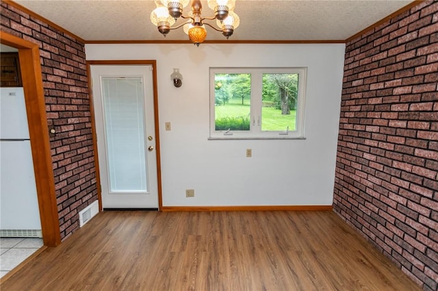 240 Connellsville St, Dunbar, PA 15431 - unfurnished dining area featuring brick wall, a chandelier, wood finished floors, baseboards, and ornamental molding