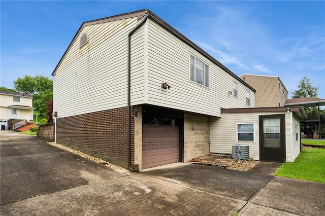 2154 Lancelot Dr, North Huntingdon, PA 15642 - rear view of property featuring a garage, concrete driveway, cooling unit, and brick siding