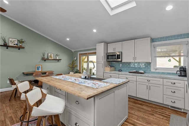 22 Green Crescent Dr, South Strabane, PA 15301 - kitchen with a sink, stainless steel microwave, vaulted ceiling, wood finished floors, and crown molding
