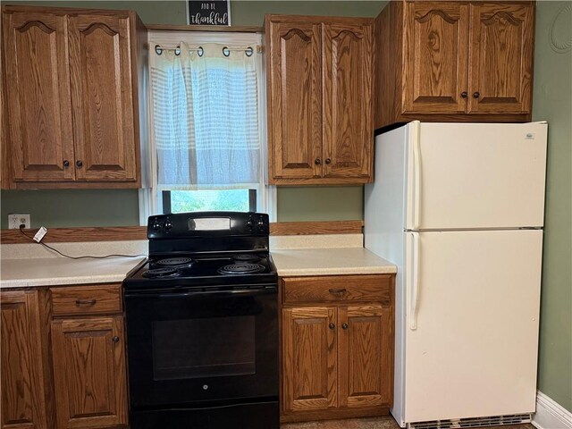 216 Center St, Slippery Rock Boro, PA 16057 - kitchen with freestanding refrigerator, black range with electric cooktop, light countertops, and brown cabinetry