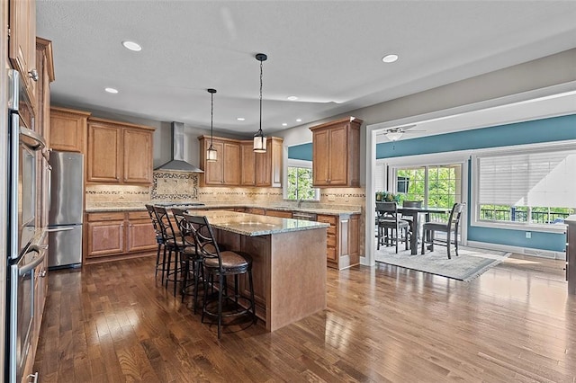 317 Buckingham Dr, Peters Twp, PA 15367 - kitchen with wall chimney range hood, appliances with stainless steel finishes, a kitchen island, dark wood finished floors, and a kitchen bar