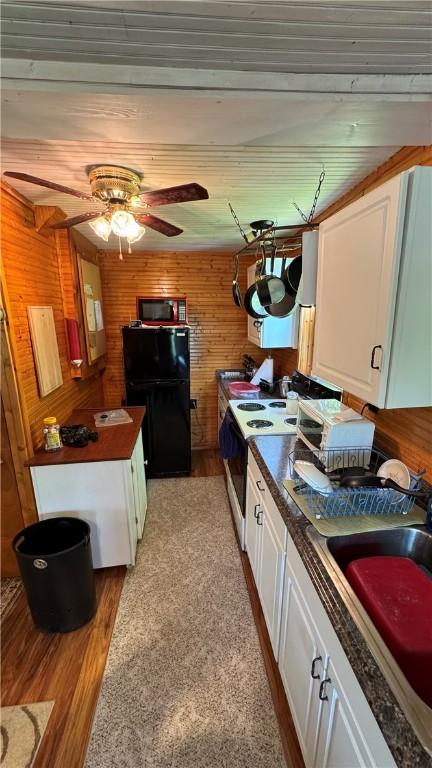 148 Rummel Rd, Bethel Twp, PA 16226 - kitchen with freestanding refrigerator, range with electric stovetop, dark countertops, white cabinets, and wood walls