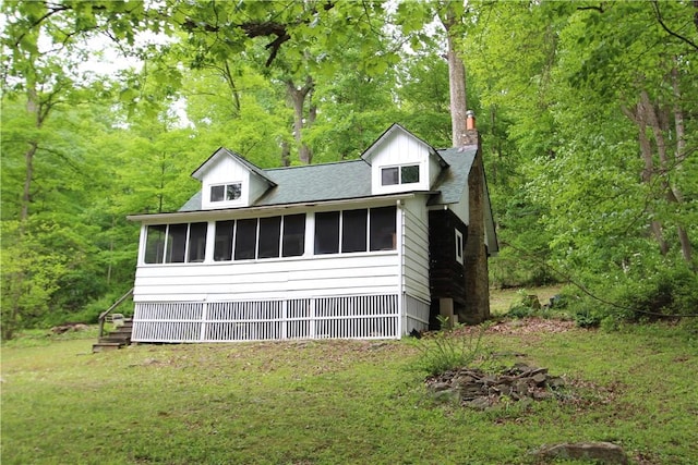 116 Camp Ln, Ligonier Twp, PA 15658 - view of front facade with a sunroom, a forest view, a chimney, a front lawn, and roof with shingles