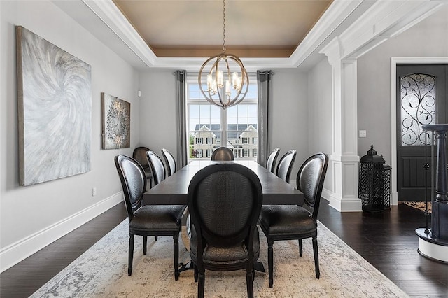 197 Wellington Cir, Peters Twp, PA 15317 - dining room with ornate columns, a tray ceiling, a chandelier, and dark wood-style floors