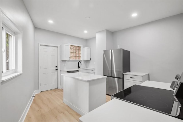 5437 Rosetta St, Garfield, PA 15206 - kitchen with freestanding refrigerator, electric stove, a center island, light wood-style floors, and white cabinetry