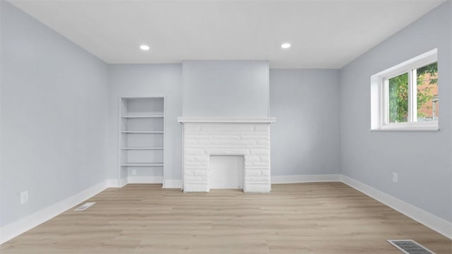 5437 Rosetta St, Garfield, PA 15206 - unfurnished living room featuring built in shelves, light wood finished floors, recessed lighting, and a stone fireplace