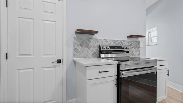 5437 Rosetta St, Garfield, PA 15206 - kitchen with stainless steel range with electric stovetop, open shelves, light countertops, white cabinetry, and backsplash