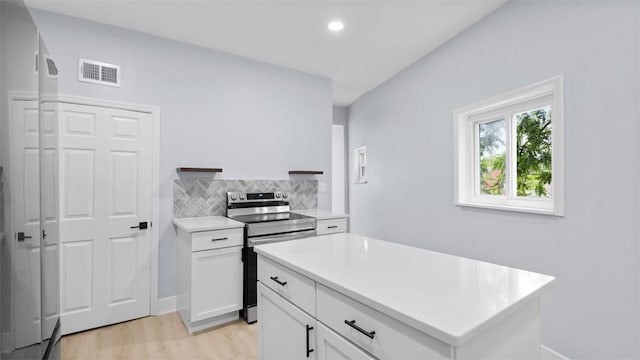 5437 Rosetta St, Garfield, PA 15206 - kitchen featuring stainless steel electric stove, light countertops, white cabinetry, light wood-type flooring, and decorative backsplash