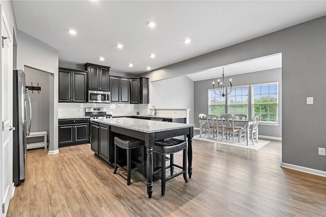 3017 Pelican Dr, Middlesex Twp, PA 16059 - kitchen with appliances with stainless steel finishes, a chandelier, a kitchen island, dark cabinets, and decorative backsplash