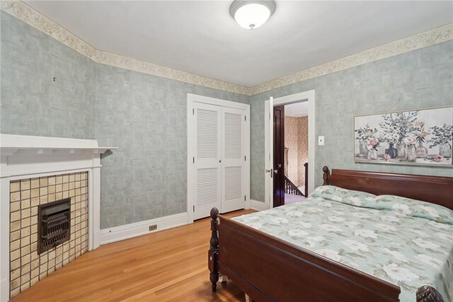 421 E Moody Ave, New Castle/2Nd, PA 16105 - bedroom with wood finished floors, a tile fireplace, baseboards, a closet, and wallpapered walls