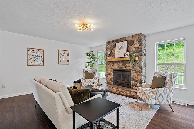 153 Birchwood Way, Irwin, PA 15642 - living room with baseboards, a textured ceiling, dark wood-style floors, and a stone fireplace