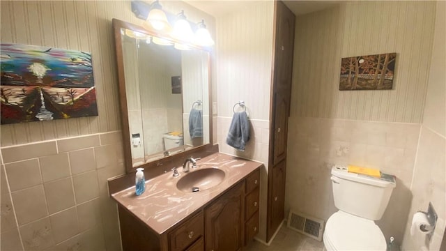 1303 Forest Ave, New Kensington, PA 15068 - half bathroom with tile walls, vanity, toilet, wallpapered walls, and wainscoting