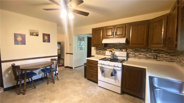 1303 Forest Ave, New Kensington, PA 15068 - kitchen with white gas stove, under cabinet range hood, backsplash, light countertops, and ceiling fan