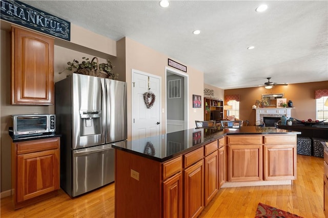 5121 Forest Ridge Dr, South Fayette, PA 15057 - kitchen featuring stainless steel refrigerator with ice dispenser, a ceiling fan, light wood-style flooring, open floor plan, and a fireplace