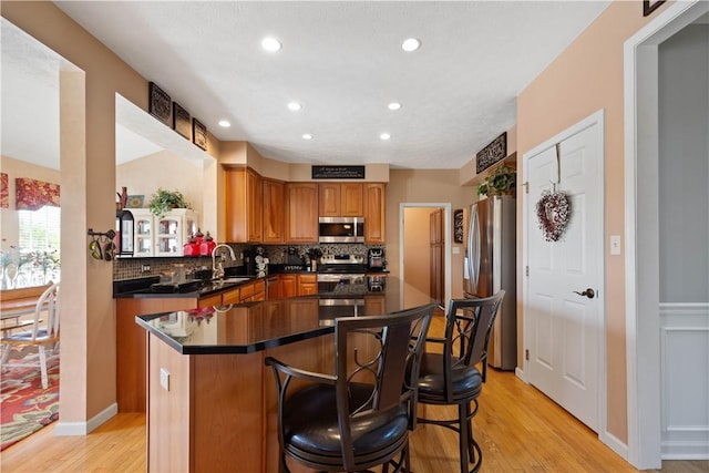 5121 Forest Ridge Dr, South Fayette, PA 15057 - kitchen with appliances with stainless steel finishes, light wood finished floors, a center island, decorative backsplash, and a breakfast bar area